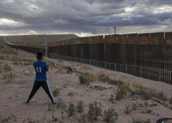 ARCHIVO  . Foto de archivo, 29 de marzo de 2017, de un joven en Anapra, Ciudad Juárez, México contemplando la construcción de una cerca metálica en la frontera frente a Sunland Park, Nuevo México. La mayoría de los estadounidenses se oponen a pagar por el muro del presidente Donald Trump en la frontera Estados Unidos México, de acuerdo con una encuesta Associated Press-NORC Center for Public Affairs Research difundida el jueves 6 de abril de 2017. (AP Foto/Rodrigo Abd, File)