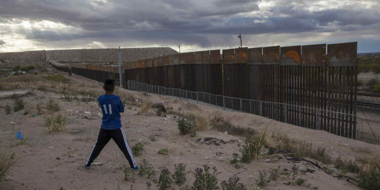 ARCHIVO  . Foto de archivo, 29 de marzo de 2017, de un joven en Anapra, Ciudad Juárez, México contemplando la construcción de una cerca metálica en la frontera frente a Sunland Park, Nuevo México. La mayoría de los estadounidenses se oponen a pagar por el muro del presidente Donald Trump en la frontera Estados Unidos México, de acuerdo con una encuesta Associated Press-NORC Center for Public Affairs Research difundida el jueves 6 de abril de 2017. (AP Foto/Rodrigo Abd, File)