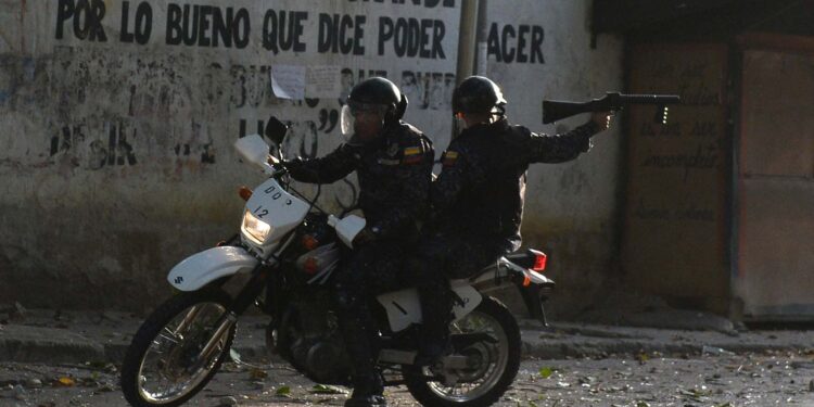 A riot policeman on a motorcycle points his gun during clashes with anti-government demonstrators in the neighborhood of Los Mecedores, in Caracas, on January 21, 2019. - A group of soldiers rose up against Venezuela's President Nicolas Maduro at a command post in northern Caracas on Monday, but were quickly arrested after posting an appeal for public support in a video, the government said. (Photo by Federico Parra / AFP)