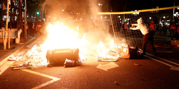 Un manifestante independentista lanza una valla al fuego durante una protesta contra la acción policial en Barcelona, España, el 26 de octubre de 2019. REUTERS/Sergio Pérez - RC1958CDA790