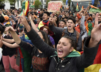 Supporters of Bolivia's main opposition presidential candidate, former president (2003-2005) Carlos Mesa, shout slogans against supporters of president and candidate Evo Morales, as both groups gather outside the hotel where the Supreme Electoral Tribunal has its headquarters to count the election votes, in La Paz, on October 21, 2019. - Evo Morales, seeking a controversial fourth term, led Bolivia's presidential election race Sunday but faces a historic second round run-off against Mesa, partial results showed. Morales had 45 percent of the vote to Mesa's 38 percent, the Supreme Electoral Tribunal announced, with most of the votes counted. (Photo by Aizar RALDES / AFP)