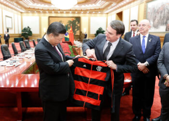 Brazil's President Jair Bolsonaro (R) gifts China's President Xi Jinping (L) a jacket at the end of the signing ceremony at the Great Hall of the People in Beijing on October 25, 2019. (Photo by Yukie Nishizawa / POOL / AFP)