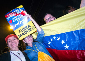 A Venezuelan resident in Costa Rica holds a sign reading "our voices are here, our hearts are in Venezuela, Maduro out" as people gather outside the house of former Costa Rican president and Nobel Peace Prize winner Oscar Arias in San Jose, Costa Rica, January 23, 2019, to thank him for his position against the government of Nicolas Maduro. - The United States and major South American nations recognised Venezuelan opposition leader Juan Guaido as interim leader on January 23 while the EU called for free elections to restore democracy, leaving President Nicolas Maduro increasingly isolated. (Photo by Ezequiel BECERRA / AFP)