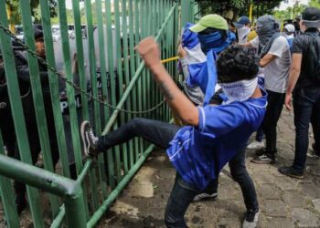 An anti-government protester kicks a riot police shield during a protest of students and relatives of political prisoners in front of a police line at the Universidad Centroamericana (UCA) in Managua on November 19, 2019. - Last week about 16 people were arrested and prosecuted for bringing water to mothers of political prisoners who were going on a hunger strike in Masaya. (Photo by INTI OCON / AFP)