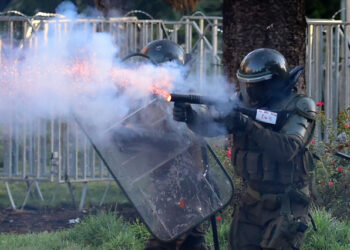 A policeman shoots at demonstrators during a protest against the government in Santiago on November 26, 2019. - The organization Human Rights Watch (HRW) presented Tuesday a report denouncing serious human rights violations by the Chilean police. (Photo by Johan ORDONEZ / AFP)