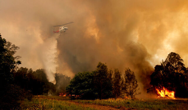 A fire bombing helicopter works to contain a bushfire along Old Bar road in Old Bar, New South Wales, Australia, November 9, 2019. AAP Image/Shane Chalker/via REUTERS  ATTENTION EDITORS - THIS IMAGE WAS PROVIDED BY A THIRD PARTY. NO RESALES. NO ARCHIVE. AUSTRALIA OUT. NEW ZEALAND OUT.