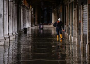 Un hombre con botas camina en Venecia. (AFP)