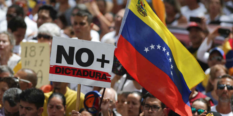 Anti-government protesters rally to demand the resignation of Venezuelan President Nicolas Maduro, as one holds a sign that reads in Spanish "No more dictatorship" in Caracas, Venezuela, Monday, March 4, 2019. The United States and about 50 other countries recognize opposition Congress President Juan Guaido as the rightful president of Venezuela, while Maduro says he is the target of a U.S.-backed coup plot. (AP Photo/Eduardo Verdugo)