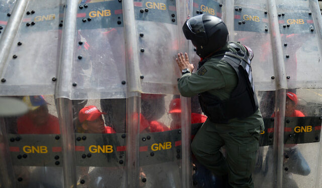 A member of the National Guard teaches deffensive tactics to civilians during military exercises to activate the integral defense entities of Miranda State, in the framework of Operation Sovereignty and Peace 2019, at the National Guard School "Ramo Verde" in Caracas, Venezuela, on September 16, 2019. - During the operation, civil forces and the Bolivarian militia learn about military tactics from the Bolivarian National Guard in order to have a rapid response in case of protests or a foreign military intervention in Venezuela. (Photo by Matias Delacroix / AFP)