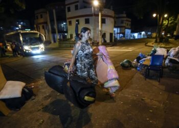 (FILES) In this file picture taken on December 18, 2019 A Venezuelan migrant carries mattresses to rest at a park in Bucaramanga, Colombia. - Dozens of Venezuelan migrants have turned the Colombian city of Bucaramanga into a large open-air bedroom. Several of the city's 244 parks are transformed into improvised camps at night. (Photo by Juan BARRETO / AFP)