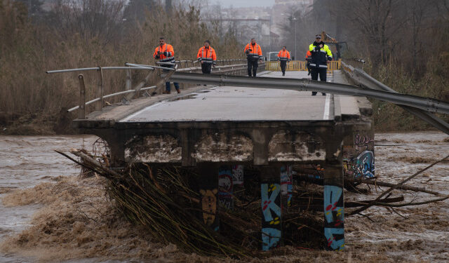 Policemen and security members walk on a fallen bridge in Malgrat de Mar, near Girona on January 22, 2020, as storm Gloria batters Spanish eastern coast. - - A winter storm which has killed three people lashed much of eastern Spain for a third day yesterday, cutting power, forcing the closure of schools and severing road and rail links. National weather agency Aemet placed most of northeastern Spain on alert because of the storm packing gusts of over 100 kilometres (60 miles) per hour, heavy snowfall, freezing rain and massive waves which smashed into seafront promenades, damaging shops and restaurants. (Photo by Josep LAGO / AFP)