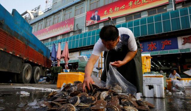 Foto de archivo. Un comerciante escoge almejas en un mercado de productos marinos en Pekín.. 27 de junio de 2018.  REUTERS/Thomas Peter