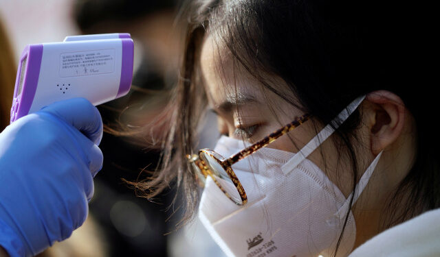 Un trabajador le toma la temperatura a una mujer en una fábrica de Shanghai, en China, el 31 de enero de 2020, en medio de una preocupación mundial por la expansión del coronavirus. REUTERS/Aly Song