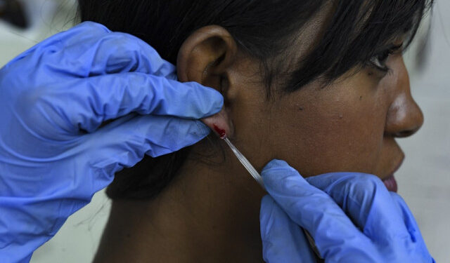 A Venezuelan Health official performs a blood test on a woman at a the Center for Malaria Studies in the Central University of Venezuela in Caracas on April 29, 2019. - In a country with an epidemic of malaria, where according to the pharmaceutical industry 85% of medicines are scarce, patients find respite at the Center for Malaria Studies, that with a very small budget depends on donations. (Photo by YURI CORTEZ / AFP)