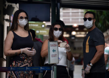 Tourists wears face masks after buying tickets at the Corcovado hill train station, to go up to see the statue of Christ the Redeemer in Rio de Janeiro, Brazil, on March 17, 2020. - Rio de Janeiro's state government closed the iconic Christ the Redeemer statue and the cable car to Sugarloaf Mountain, two of the city's most famous attractions, as an emergency measure to stop the spread of the new coronavirus COVID-19. (Photo by MAURO PIMENTEL / AFP)