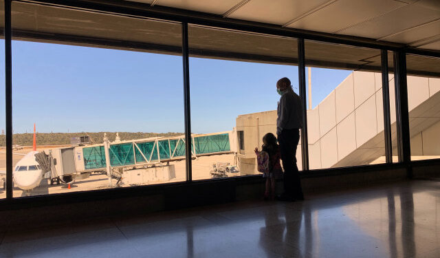 A man wearing a protective mask in response to the spreading of coronavirus (COVID-19) stand near a child at Simon Bolivar international airport in Maiquetia, Venezuela, March 15, 2020. REUTERS/Carlos Jasso