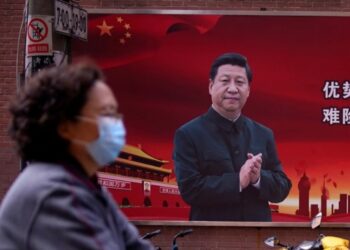 Una mujer con una máscara protectora es vista más allá de un retrato del mandatario chino Xi Jinping en una calle cuando el país es golpeado por un brote de coronavirus, en Shanghai, China (Reuters)