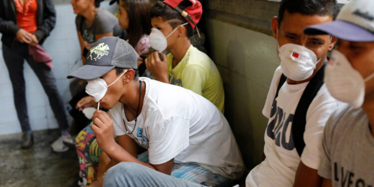 People outside a metro station wear face masks distributed by members of the Taiwan and Venezuela Parliamentary Friendship team, in response to the spreading coronavirus (COVID-19), in Caracas, Venezuela March 12, 2020. REUTERS/Carlos Jasso