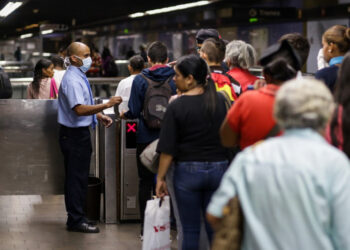 A subway worker wearing a face mask (L) receive tickets at the subway station in the face of the global COVID-19 coronavirus pandemic, in Caracas, on March 13, 2020. (Photo by CRISTIAN HERNANDEZ / AFP)