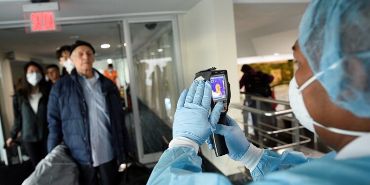 A worker from Ecuador's Health Ministry uses a thermal scanner to check passengers arriving from the U.S., as part of the security measures due to the outbreak of the coronavirus (COVID-19), at Jose Joaquin de Olmedo International Airport in Guayaquil, Ecuador March 13, 2020. REUTERS/Santiago Arcos