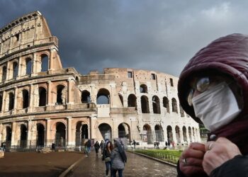 A man wearing a protective mask passes by the Coliseum in Rome on March 7, 2020 amid fear of Covid-19 epidemic. - Italy on March 6, 2020 reported 49 more deaths from the new coronavirus, the highest single-day toll to date, bringing the total number of fatalities over the past two weeks to 197. (Photo by Alberto PIZZOLI / AFP)