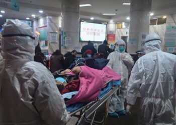 In this photo taken on January 25, 2020, medical staff wearing protective clothing to protect against a previously unknown coronavirus arrive with a patient at the Wuhan Red Cross Hospital in Wuhan. - The number of confirmed deaths from a viral outbreak in China has risen to 54, with authorities in hard-hit Hubei province on January 26 reporting 13 more fatalities and 323 new cases. (Photo by Hector RETAMAL / AFP)