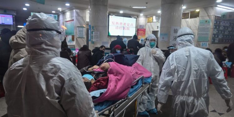 In this photo taken on January 25, 2020, medical staff wearing protective clothing to protect against a previously unknown coronavirus arrive with a patient at the Wuhan Red Cross Hospital in Wuhan. - The number of confirmed deaths from a viral outbreak in China has risen to 54, with authorities in hard-hit Hubei province on January 26 reporting 13 more fatalities and 323 new cases. (Photo by Hector RETAMAL / AFP)