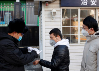 Un guardia de seguridad toma la temperatura de personas que llegan a trabajar a un edificio de oficinas en Pekín, China, 3 de marzo de 2020. REUTERS/Thomas Peter