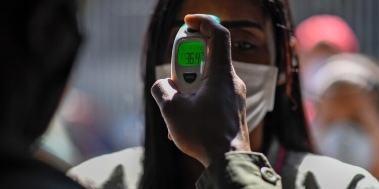 A member of the Bolivarian National Guard checks a woman's temperature as a preventive measure against the spread of the new coronavirus, COVID-19, outside a municipal market in Caracas, on March 20, 2020. (Photo by Federico PARRA / AFP)