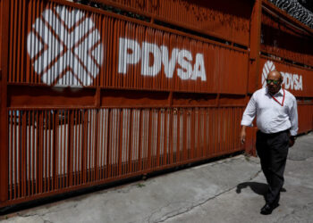Foto de archivo de un hombre pasando por una puerta con el logotipo corporativo de la petrolera estatal venezolana PDVSA en Caracas. 3 de noviembre de 2017. REUTERS/Marco Bello