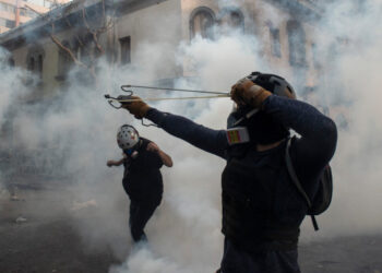 A demonstrators aims a sling at the police during a protest against Chilean President Sebastian Pinera's government in Santiago on March 02, 2020. (Photo by Martin BERNETTI / AFP)