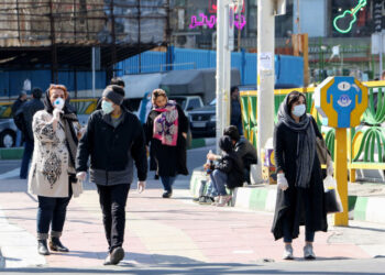 Iranian pedestrians walk while wearing protective masks in Tehran on March 10, 2020 amid the spread of coronavirus in the country. - Iran today reported 54 new deaths from the novel coronavirus in the past 24 hours, the highest single-day toll since the start of the country's outbreak. (Photo by ATTA KENARE / AFP)