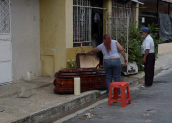 A woman looks into a coffin holding the dead body of her mother after she died at home yesterday, during the outbreak of the coronavirus disease (COVID-19), in Guayaquil, Ecuador March 31, 2020. REUTERS/Vicente Gaibor del Pino NO RESALES. NO ARCHIVES