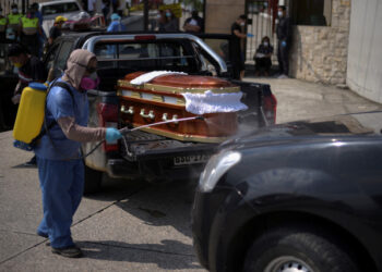 A worker sprays disinfectant on a vehicle carrying a coffin lined up to enter a cemetery as Ecuador's government announced on Thursday it was building a "special camp" in Guayaquil for coronavirus disease (COVID-19) victims, in Guayaquil, Ecuador April 2, 2020. REUTERS/Vicente Gaibor del Pino NO RESALES. NO ARCHIVES