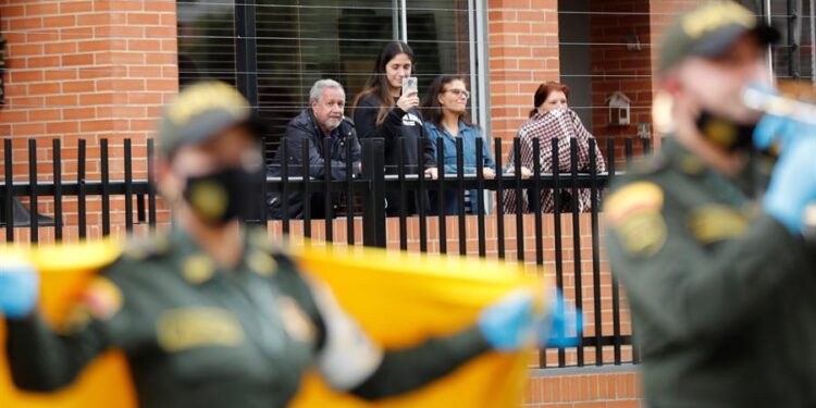 Ciudadanos bajo cuarentena salen este viernes a los balcones de sus hogares mientras la Policía realiza un espectáculo de música tropical colombiana, en el barrio Pontevedra de Bogotá (Colombia). Un grupo de policías colombianos llega cada día con bailes y cantos a un barrio de Bogotá para entretener y animar a las personas confinadas en sus hogares por la cuarentena que busca mitigar la propagación del coronavirus. La jornada de este viernes se hizo en un camión que fue adaptado como tarima y en la que los uniformados desplegaron frente a un conjunto residencial una presentación musical con ritmos tropicales colombianos. EFE/ Mauricio Dueñas Castañeda