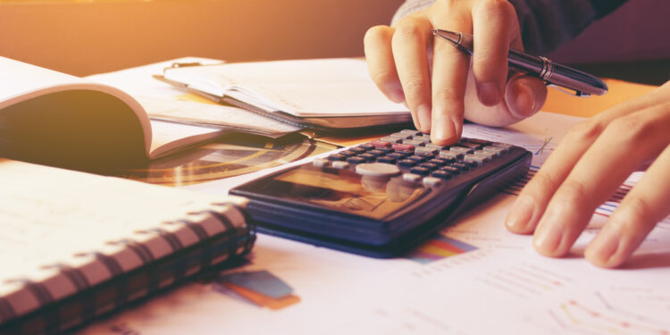 Woman using calculator with doing finance at home office.