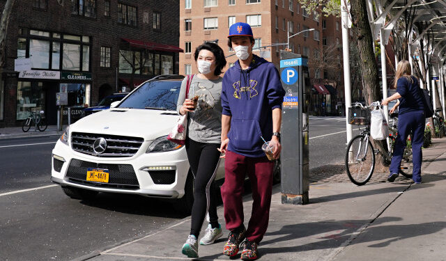 NEW YORK, NEW YORK - APRIL 07: A couple walk while wearing protective masks during the coronavirus pandemic on April 07, 2020 in New York City. COVID-19 has spread to most countries around the world, claiming almost 70,000 lives with infections nearing 1.3 million people.   Cindy Ord/Getty Images/AFP