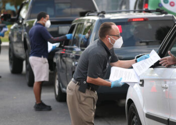 HIALEAH, FLORIDA - APRIL 08: Eddie Rodriguez (R) and other City of Hialeah employees hand out unemployment applications to people in their vehicles in front of the John F. Kennedy Library on April 08, 2020 in Hialeah, Florida. The city is distributing the printed unemployment forms to residents as people continue to have issues with access to the state of Florida’s unemployment website in the midst of widespread layoffs due to businesses closing during the coronavirus pandemic. (Photo by Joe Raedle/Getty Images)