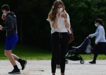 Imagen: Una mujer con mascarilla utilizando su teléfono (Getty)