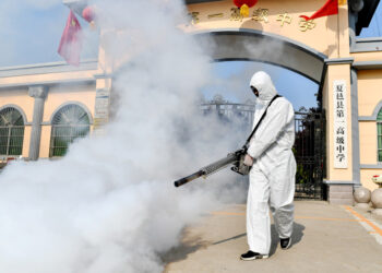 A volunteer sprays disinfectant at a school as the school prepares for students returning after the term opening was delayed due to the COVID-19 coronavirus outbreak, in Shangqiu in China's central Henan province on April 3, 2020. (Photo by STR / AFP) / China OUT