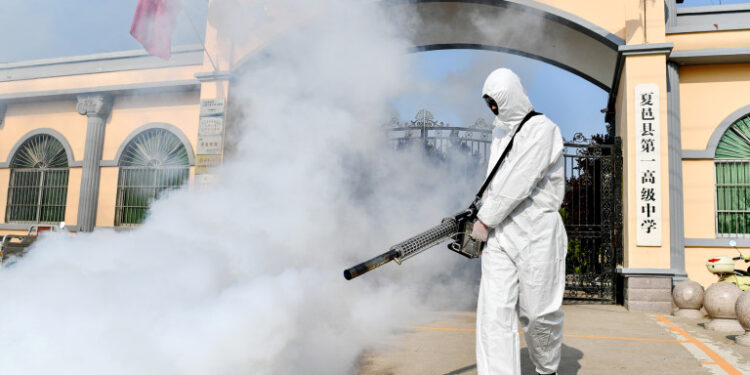 A volunteer sprays disinfectant at a school as the school prepares for students returning after the term opening was delayed due to the COVID-19 coronavirus outbreak, in Shangqiu in China's central Henan province on April 3, 2020. (Photo by STR / AFP) / China OUT