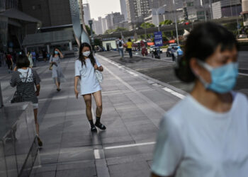 Women wearing a face mask walk in a street of Wuhan, in Chinas central Hubei province on May 18, 2020. - Authorities in the pandemic ground zero city of Wuhan have ordered mass COVID-19 testing for all 11 million residents after a new cluster of cases emerged over the weekend. (Photo by Hector RETAMAL / AFP)