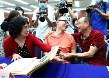 This photo taken on May 18, 2020 shows Mao Yin (C) speaking with his mother Li Jingzhi (L) and father Mao Zhenping (R) in Xian, in China's northern Shaanxi province. - A Chinese man who was kidnapped as a toddler 32 years ago has been reunited with his biological parents, after police used facial recognition technology to track him down. (Photo by STR / AFP) / China OUT