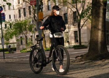 NEW YORK, NY - MAY 04: A woman walks a bike while wearing a protective mask during the coronavirus pandemic on May 4, 2020 in New York City. COVID-19 has spread to most countries around the world, claiming over 252,000 lives with over 3.6 million infections reported.   Cindy Ord/Getty Images/AFP