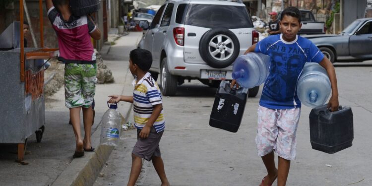 TO GO WITH AFP STORY by Gerardo Guarache
Boys carry empty bottles and cans to fill them with water in Caucaguita, Caracas, on June 20, 2014. Water use in Caracas and its suburbs, home to five million people, is being rationed since the beginning of May and will continue for two more months, due to drought. Even when fully operating and unaffected by drought, water supply levels in the capital area are below international standards, capable of providing 340 liters per person per day, which is sufficient for household consumption but falls short of commercial and industrial demands.  AFP PHOTO/Leo RAMIREZ