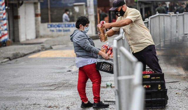 A man delivers bread to a woman at the Santa Cruz neighborhood in Medellin, Colombia on June 6, 2020. - Authorities placed the Santa Cruz neighborhood under strickled lockdown after an outbreak of Covid-19 coronavirus cases. (Photo by JOAQUIN SARMIENTO / AFP)