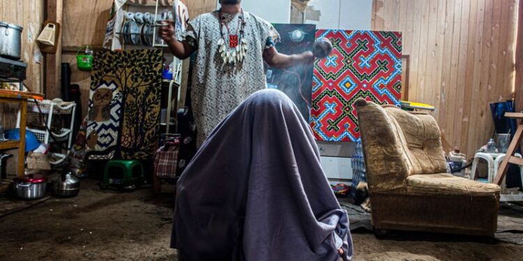 Una mujer (debajo de una manta) respira vapor de hierbas medicinales durante una ceremonia de curación en la comunidad de Cantagallo, donde habitan unas 300 familias del grupo étnico Shipibo Conibo, en Lima el 18 de junio de 2020. (ERNESTO BENAVIDES/AFP via Getty Images)