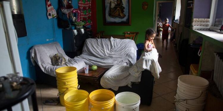 Varios cubos, algunos de ellos llenos con agua proporcionada por un camión cisterna gubernamental, en la sala de estar de una casa en el vecindario de Petare, en Caracas, Venezuela, el 15 de junio de 2020. El colapso económico de Venezuela ha dejado a la mayoría de los hogares sin un suministro de agua corriente confiable. ARIANA CUBILLOS AP