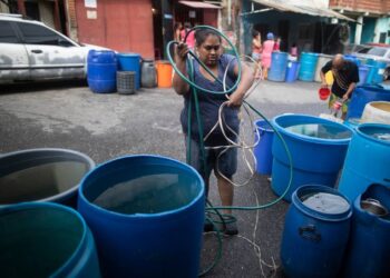 Una mujer desenreda un cable eléctrico y una manguera para bombear agua desde un gran recipiente proporcionado por un camión cisterna del gobierno, en el vecindario humilde de Petare, en Caracas, Venezuela, el 10 de junio de 2020. La crisis de agua no es nada nuevo en Venezuela, pero el agua es todavía más importante hoy en día para protegerse de la pandemia del coronavirus. ARIANA CUBILLOS AP