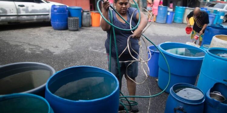 Una mujer desenreda un cable eléctrico y una manguera para bombear agua desde un gran recipiente proporcionado por un camión cisterna del gobierno, en el vecindario humilde de Petare, en Caracas, Venezuela, el 10 de junio de 2020. La crisis de agua no es nada nuevo en Venezuela, pero el agua es todavía más importante hoy en día para protegerse de la pandemia del coronavirus. ARIANA CUBILLOS AP